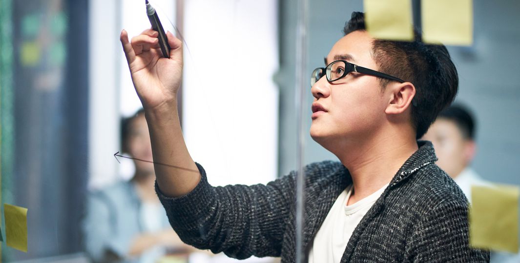 Person teaching in front of a board with post its