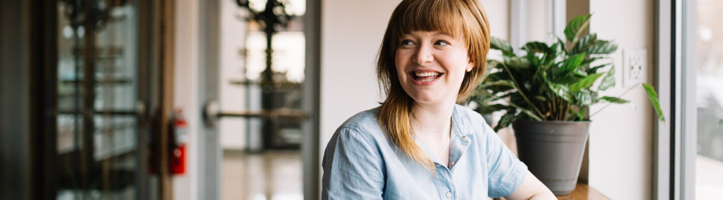 Person smiling with a plant in the background, to illustrate enterprise training from BRE Academy