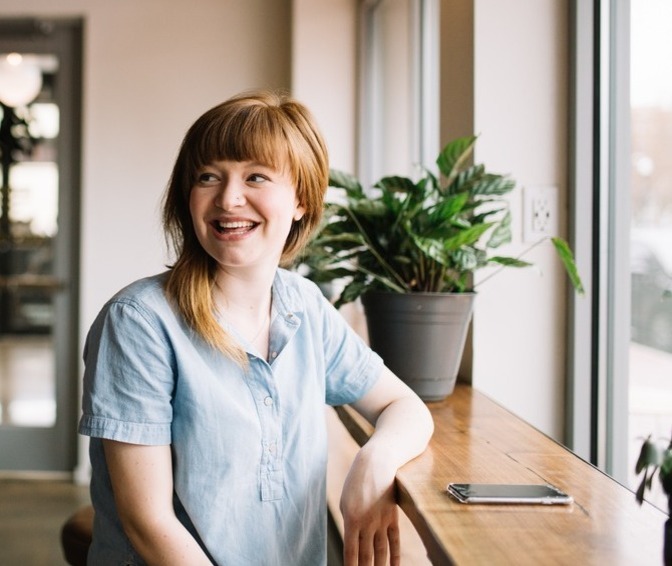 Woman smiling with a plant in the background